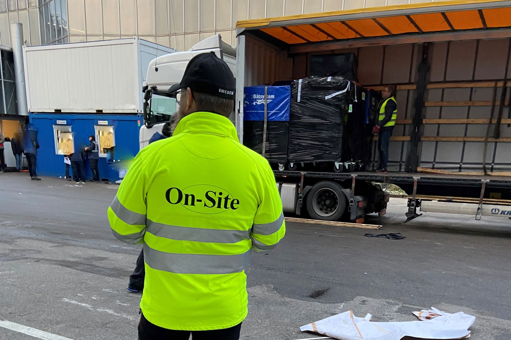En man stående i en gul jacka med företagets logotyp